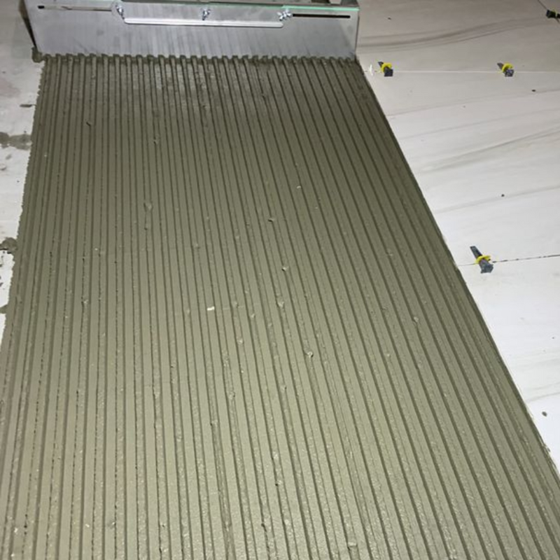 Adjustable notched trowel for fast and equal application of adhesive on the floor